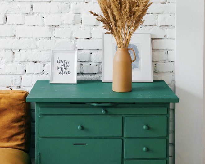 well decorated green bedside drawer with photo frames and a vase 