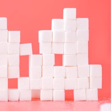 many sugar cubes stacked to form a wall against a pink background